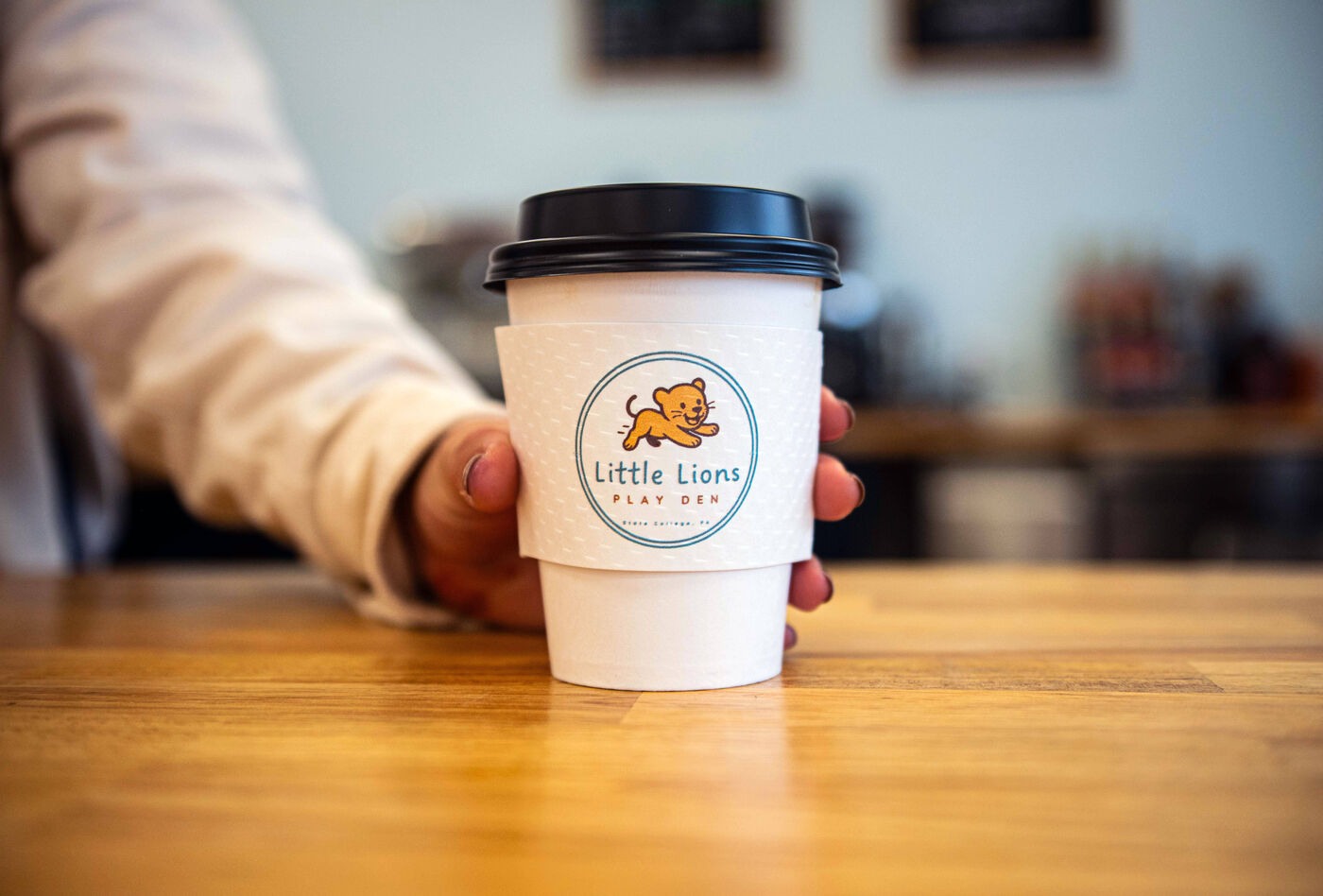 A Little Lions branded coffee cup on the café counter